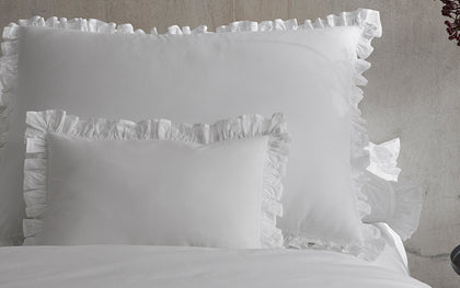 White Georgia ruffled pillows and duvet arranged on a bed.