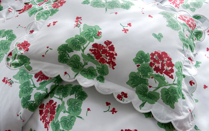 White Geranium print pillow with a scalloped edge in red and green floral pattern.
