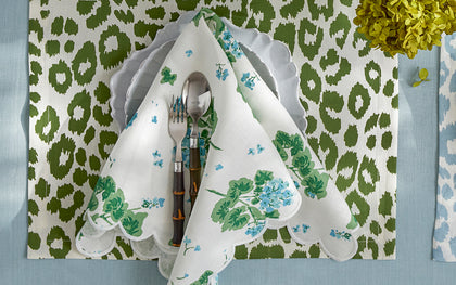 Green leopard print placemat paired with a blue Geranium print napkin, set on a table.