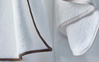 White Giza towels hanging with brown and tan piped trim.