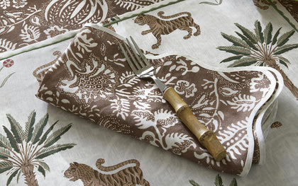 Brown and white Tiger Palm print napkin folded with a fork, beside a matching tablecloth.