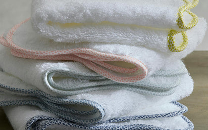 White Jasper towels with pebbled trim in yellow, pink, and gray, folded in a stack.