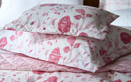 Pink Khilana floral print quilted pillows, layered on a bed.