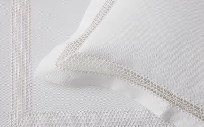 White Lace Pique pillow with a woven lace trim border, layered on a bed.