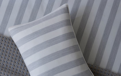 Lana grey and white striped pillow on a bed