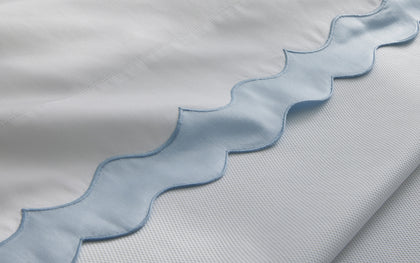 White Lorelei scalloped bedding with a light blue trim.