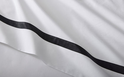 White Lowell bedding with a black ribbon trim.