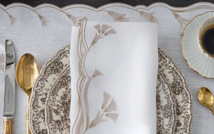 Marcella embroidered table linens in green, blue, and tan on white linen