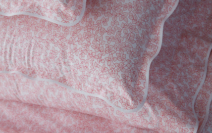 Pink Margot vine-print scalloped bedding, layered on a bed.