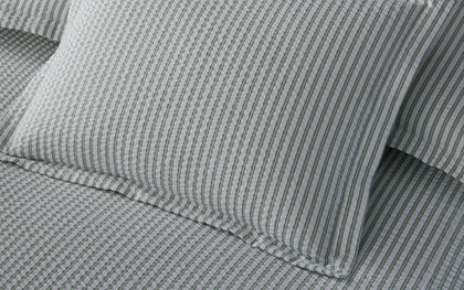 Green-striped Matteo bedding layered on a bed.