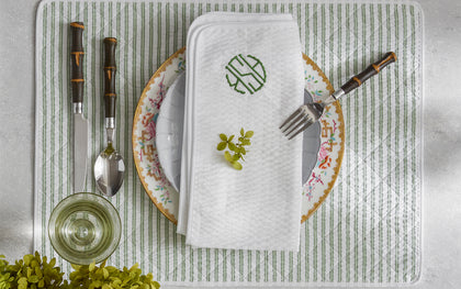 Green-striped Matteo placemat and monogrammed napkin with floral china and bamboo-handled flatware.