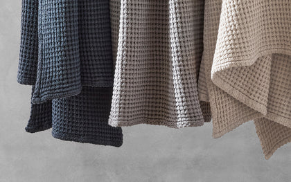 Nico waffle-weave towels hanging in navy, grey, and tan