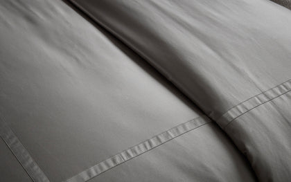 Gray Nocturne sateen sheets layered on a bed.