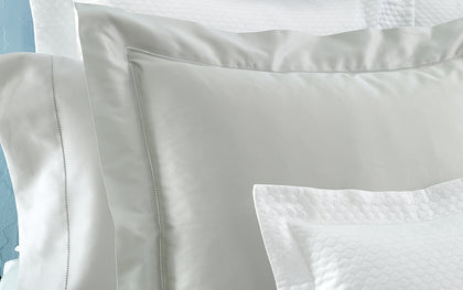 White and gray Nocturne Hemstitch shams layered with quilted pillows.