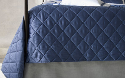 Navy diamond-quilted Nocturne Quilt coverlet styled on a four-poster bed.