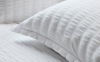 White seersucker-textured Panama shams and bedding layered on a bed.
