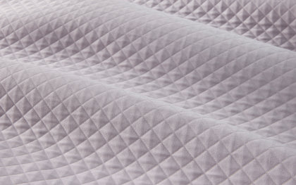 Lavender diamond-quilted Petra coverlet layered on a bed.