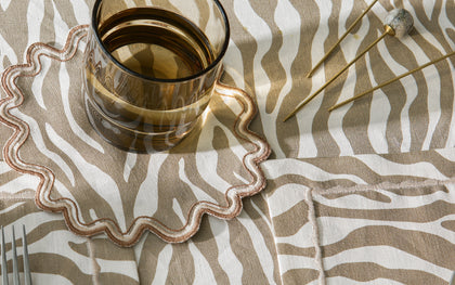 Regine zebra-stripe table linens with a scalloped edge and amber glassware