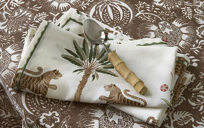 White Tiger Palm napkin with tiger and palm print on a brown paisley tablecloth.