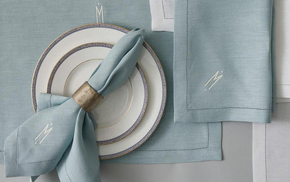 Blue Valentina Hemstitch placemat and monogrammed napkin beside Greek key china plates.