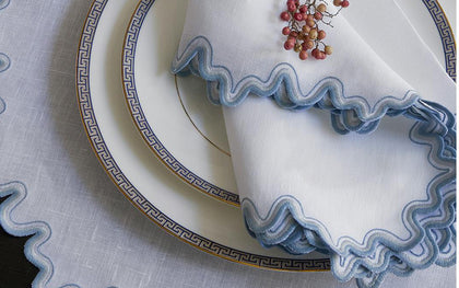 White Wave placemat and napkin with blue wavy trim beside Greek key china.