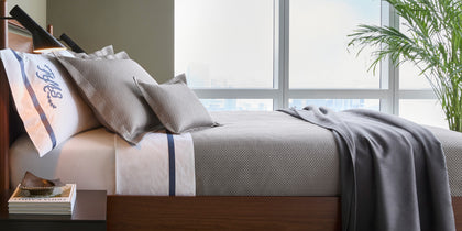 Gray Alba textured pique bedding with a monogrammed sham, styled on a bed near a window.