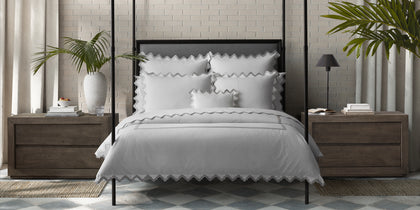 White Aziza bedding with gray wavy trim, styled on a bed with a four-poster frame.