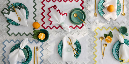 Aziza wavy-edge placemats in green, red, blue, and yellow, set with green plates and oranges.