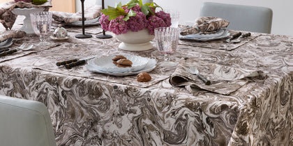 Brown Balthazar marbled-print tablecloth set for dinner with purple hydrangeas and scalloped plates.