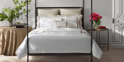 White Bel Tempo Nocturne bedding with red triple-stripe trim, styled on a bed with a four-poster frame.