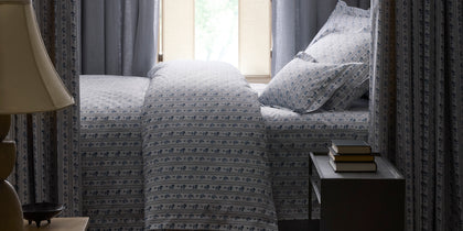 Blue and white Cabanon Stripe floral bedding styled on a canopy bed in a moody bedroom.
