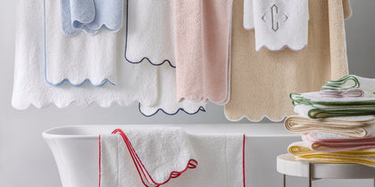 White Cairo Scallop towels with colorful scalloped edges, hanging above and draped over a tub.