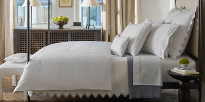 White Casablanca bedding with gray diamond-embroidered trim, styled on a bed near a lattice cabinet.