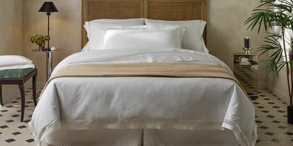 White Cecily bedding with lattice lace trim, styled on a bed with a rattan headboard.