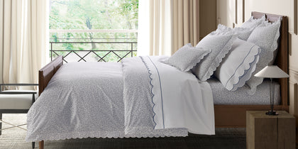 Navy speckled Celine print scalloped bedding, styled on a bed near a balcony window.