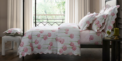 Pink Charlotte allium-print bedding styled on a four-poster bed near a balcony window.