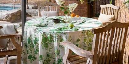 Green Citrus Garden print round tablecloth set on an outdoor patio table beside a pool.