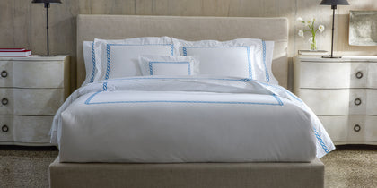 White Classic Chain bedding with blue chain-link embroidered border, styled on a bed.