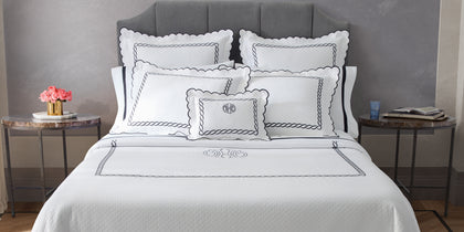 Classic Chain white matelassé bedding with a monogrammed pillow on a bed
