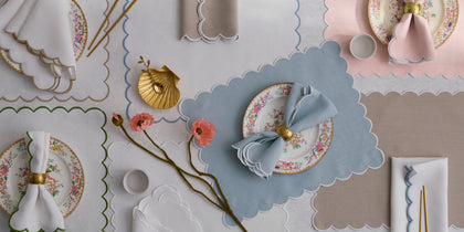 Dakota scalloped placemats in blue, pink, and tan set with floral china and napkins.
