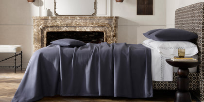 Charcoal Dream Modal sheets styled on a bed near a marble fireplace.