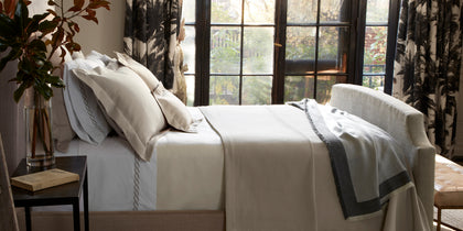 White Elliot textured pique bedding styled on a bed near a window with palm-print curtains.
