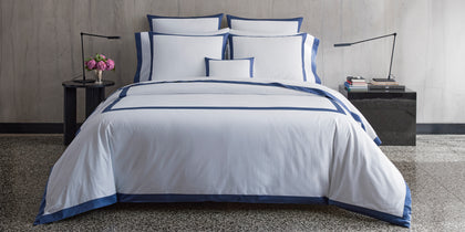White Emory bedding with a navy tailored border, styled on a bed.