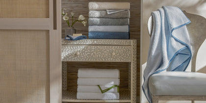 Enzo bath towels in a bathroom, with a pale blue towel draped over a chair.