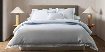 White Essex bedding with a blue stitched border, styled on a bed.
