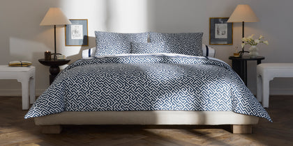 Navy and white Gabriel geometric print bedding, styled on a low platform bed.
