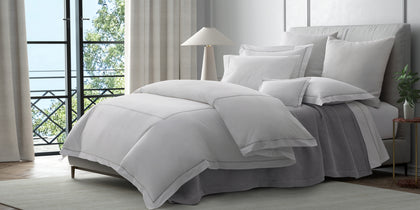 White Gatsby bedding with gray trim, styled on a bed near a window.