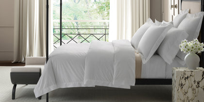 White Gatsby hemstitch bedding on a four poster bed by an open window.