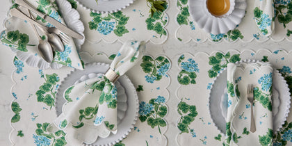 Blue Geranium print table linens set with scalloped placemats, seen from above.