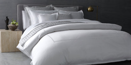 White Grace bedding with a lace trimmed border, styled on a bed.